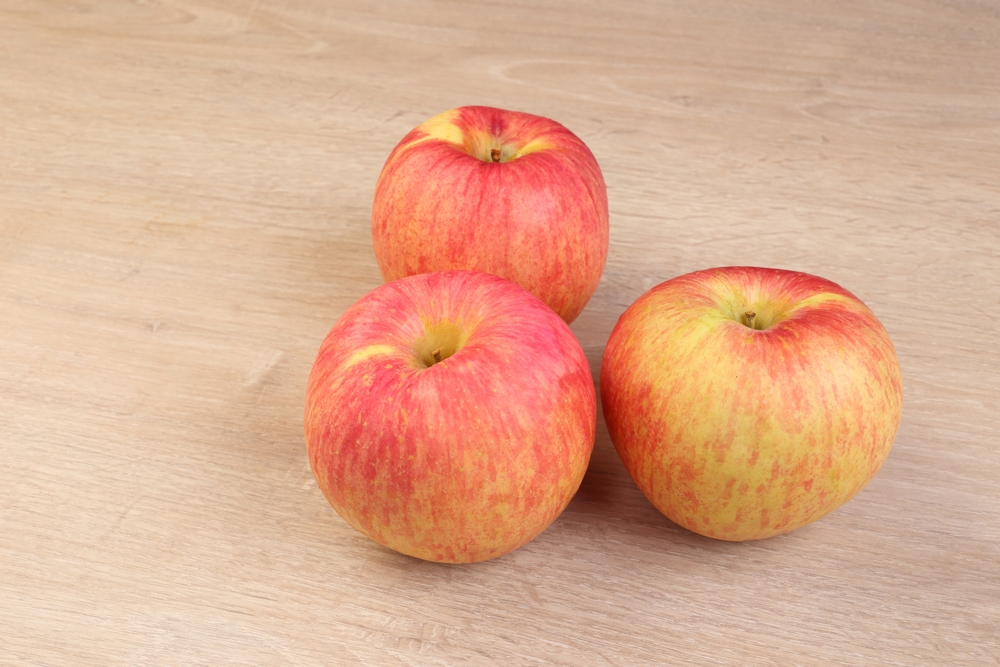 Three Fuji apples on a chopping board