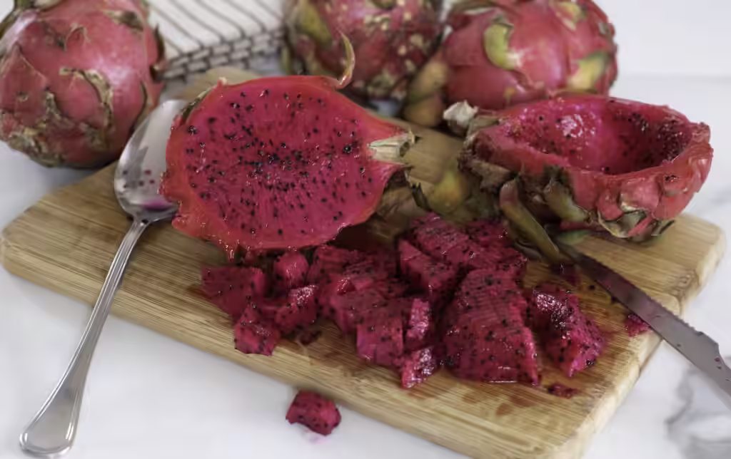 Vibrant red-fleshed dragon fruit cut in half and flesh scooped out.